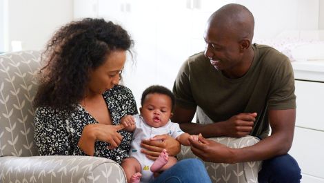 Two adults hold a smiling baby